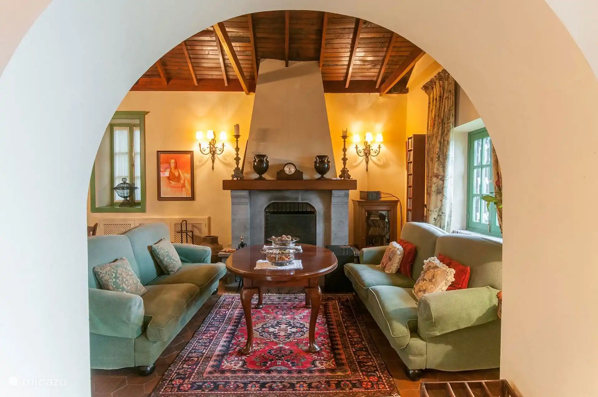 Living room with stone arch, fireplace and sofas under wooden roof