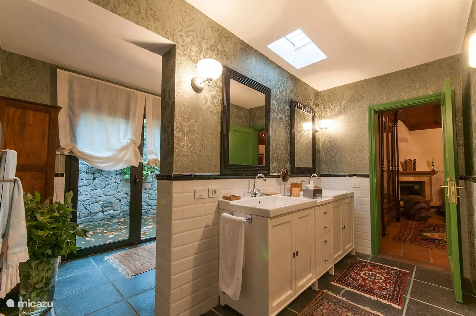 Bathroom with double sink, skylight and exposed stone wall