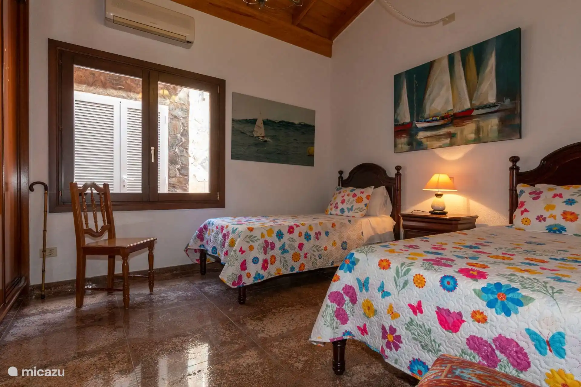 Slaapkamer met twee eenpersoonsbedden, airconditioning en buitenraam.