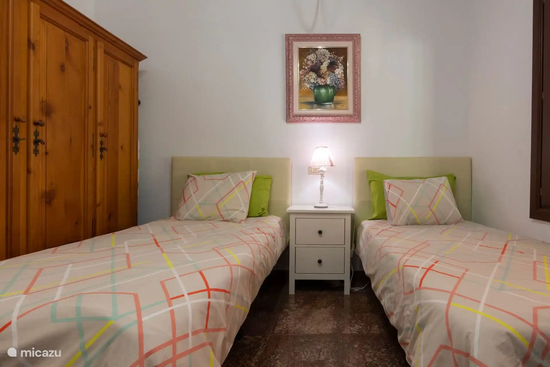 Slaapkamer met twee eenpersoonsbedden en een houten kledingkast.