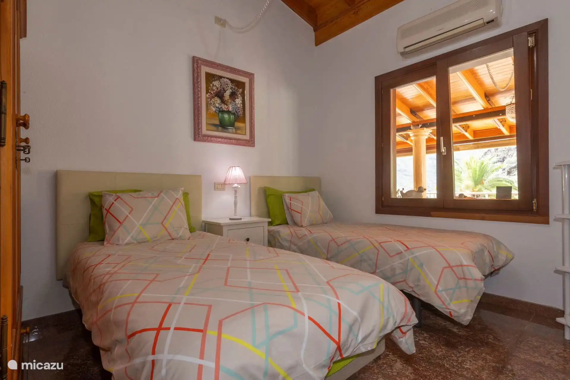 Slaapkamer met twee eenpersoonsbedden, raam naar het terras en airconditioning.