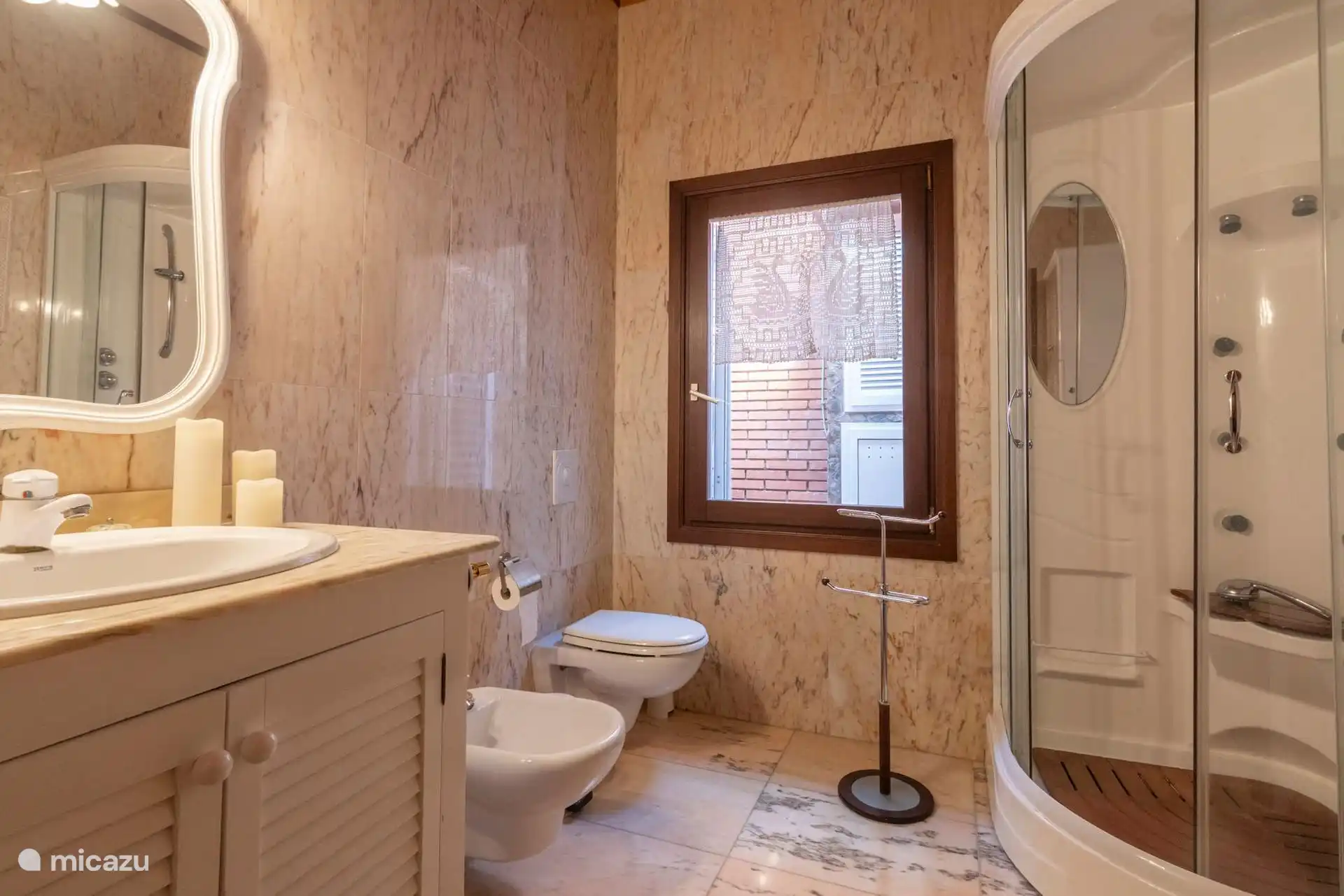 Tweede badkamer met cabinedouche, bidet en wastafel met spiegel.