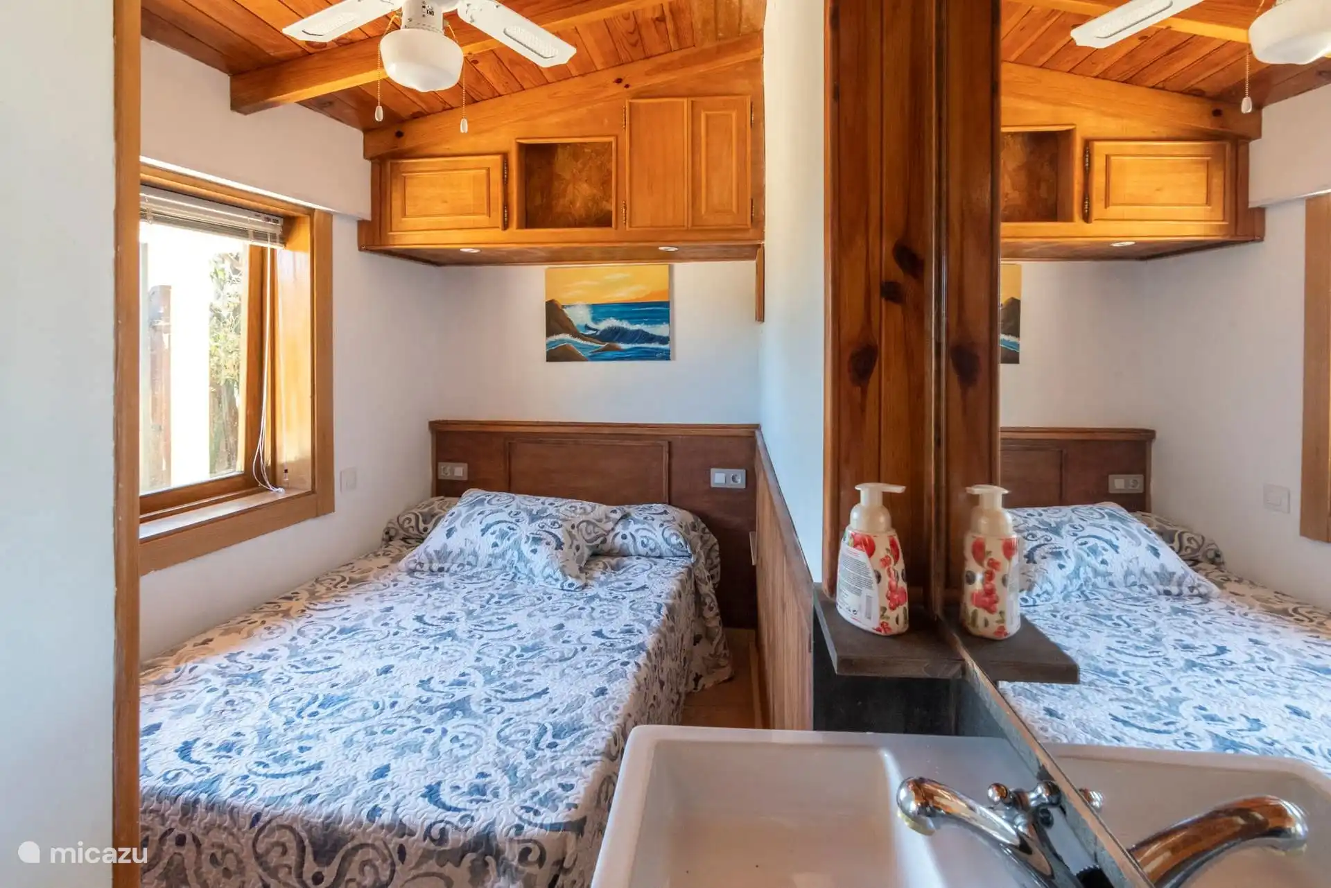 Slaapkamer met twee eenpersoonsbedden en een plafondventilator.