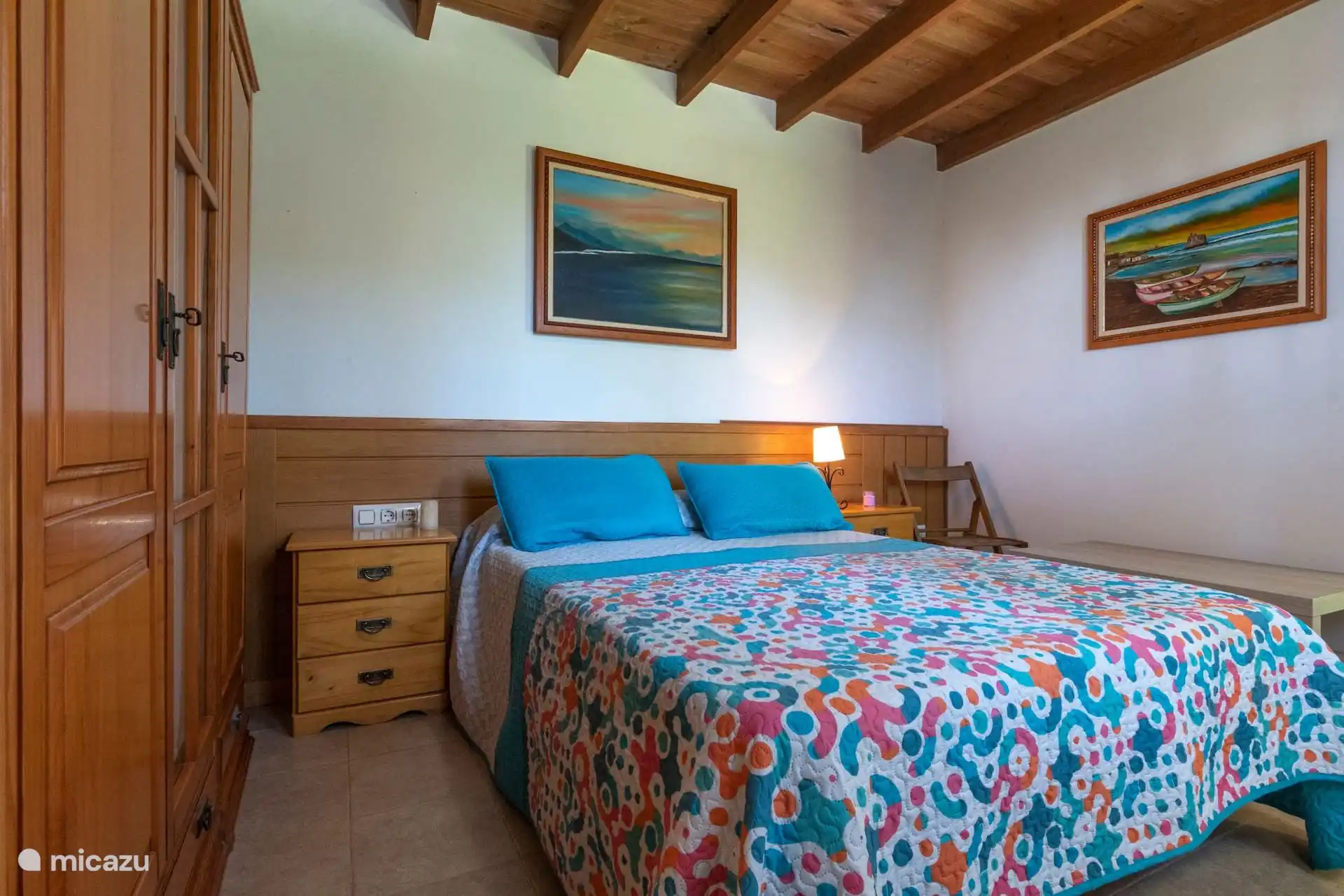 Slaapkamer met tweepersoonsbed en houten kledingkast.