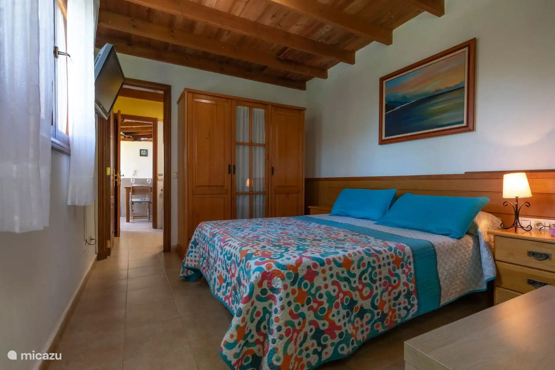 Slaapkamer met tweepersoonsbed, televisie en ingebouwde kledingkast.