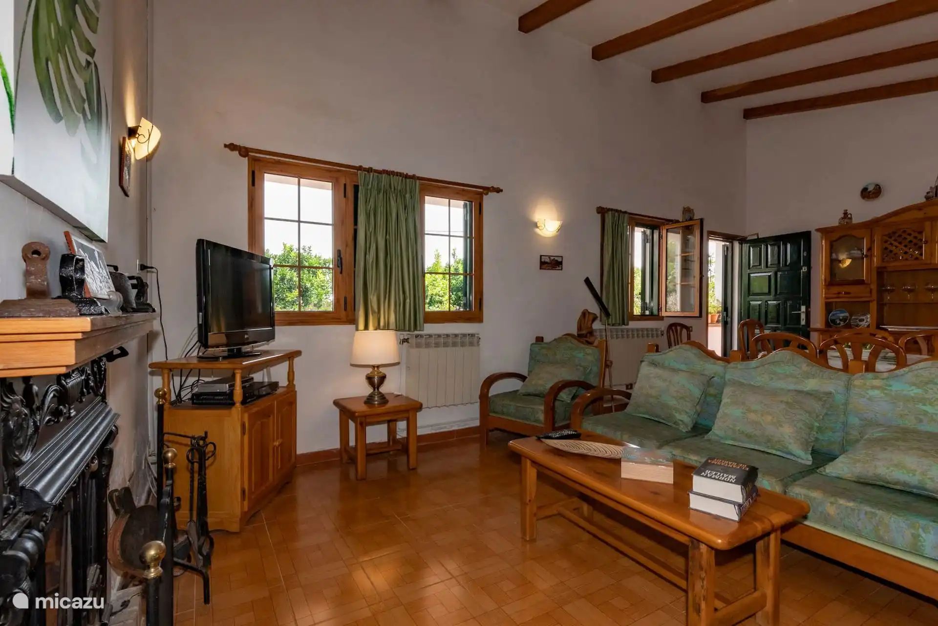 Otra vista del salón, con sofá, mesa baja y chimenea de hierro.