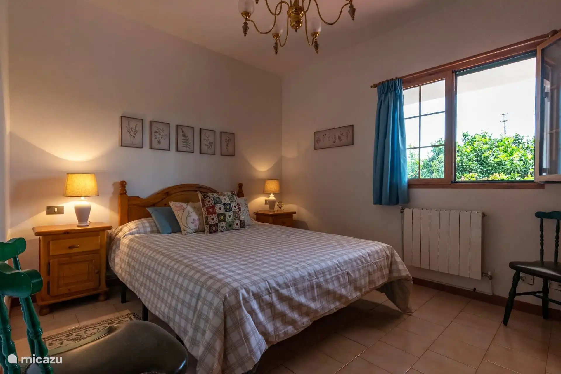 Dormitorio con cama de matrimonio, mesillas y ventana al jardín.