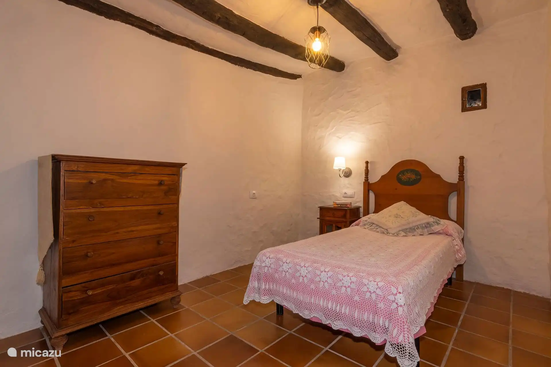 Dormitorio individual con cómoda de madera y mesilla.