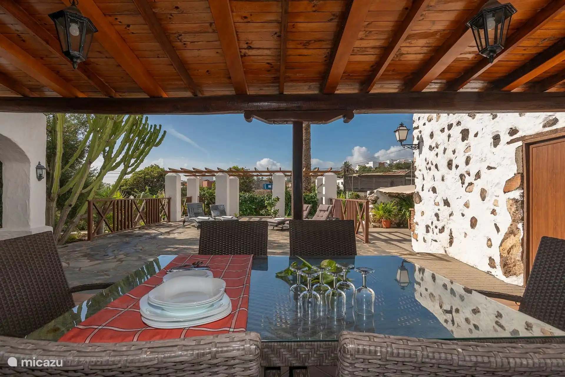 Porche con mesa y sillas de exterior, junto a la piedra volcánica.