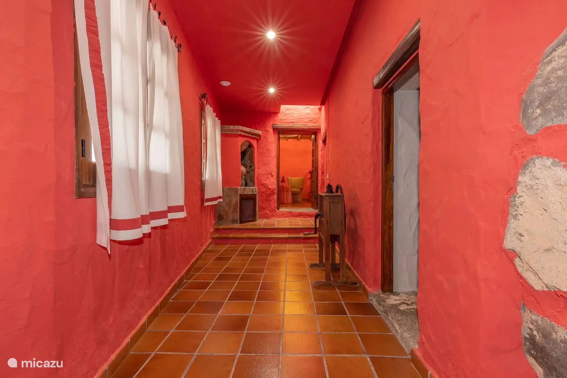 Pasillo de la casa con el suelo de barro y el muro de piedra.
