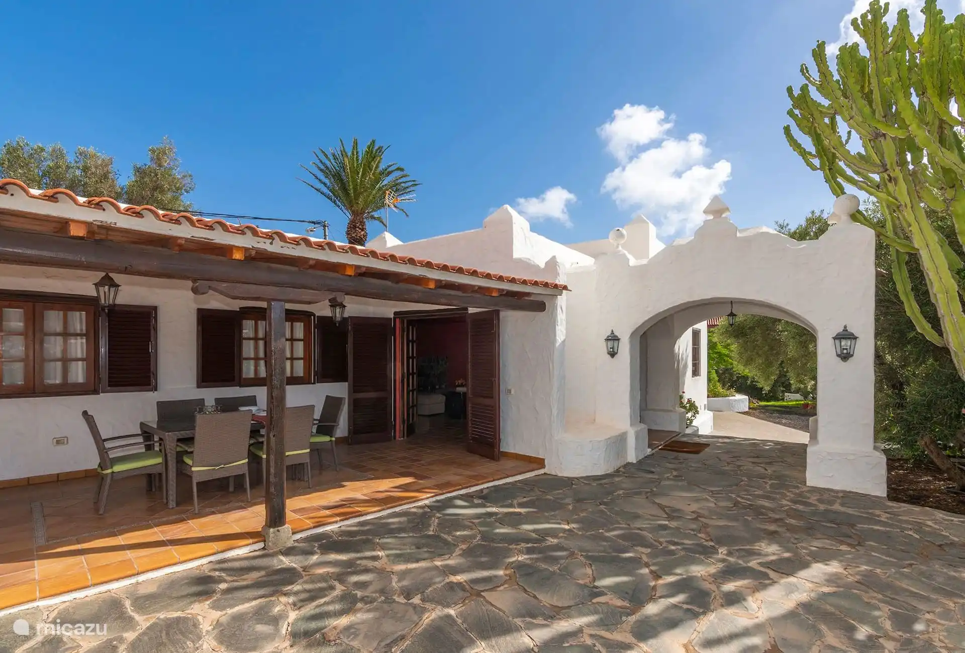 Fachada de la casa con el porche corrido y el arco de entrada.