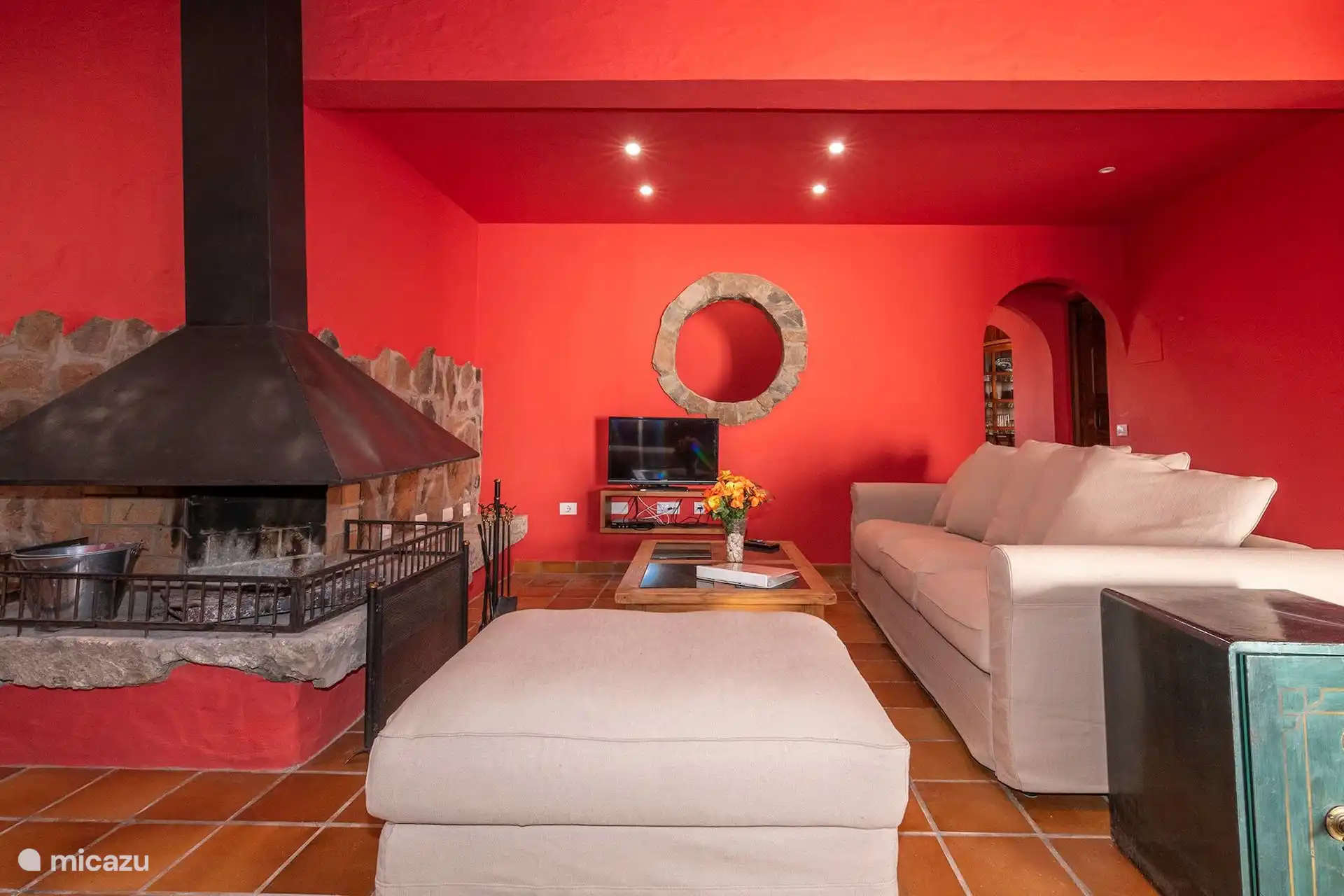 Rincón de estar junto al dormitorio, con butacas y mesa camilla.