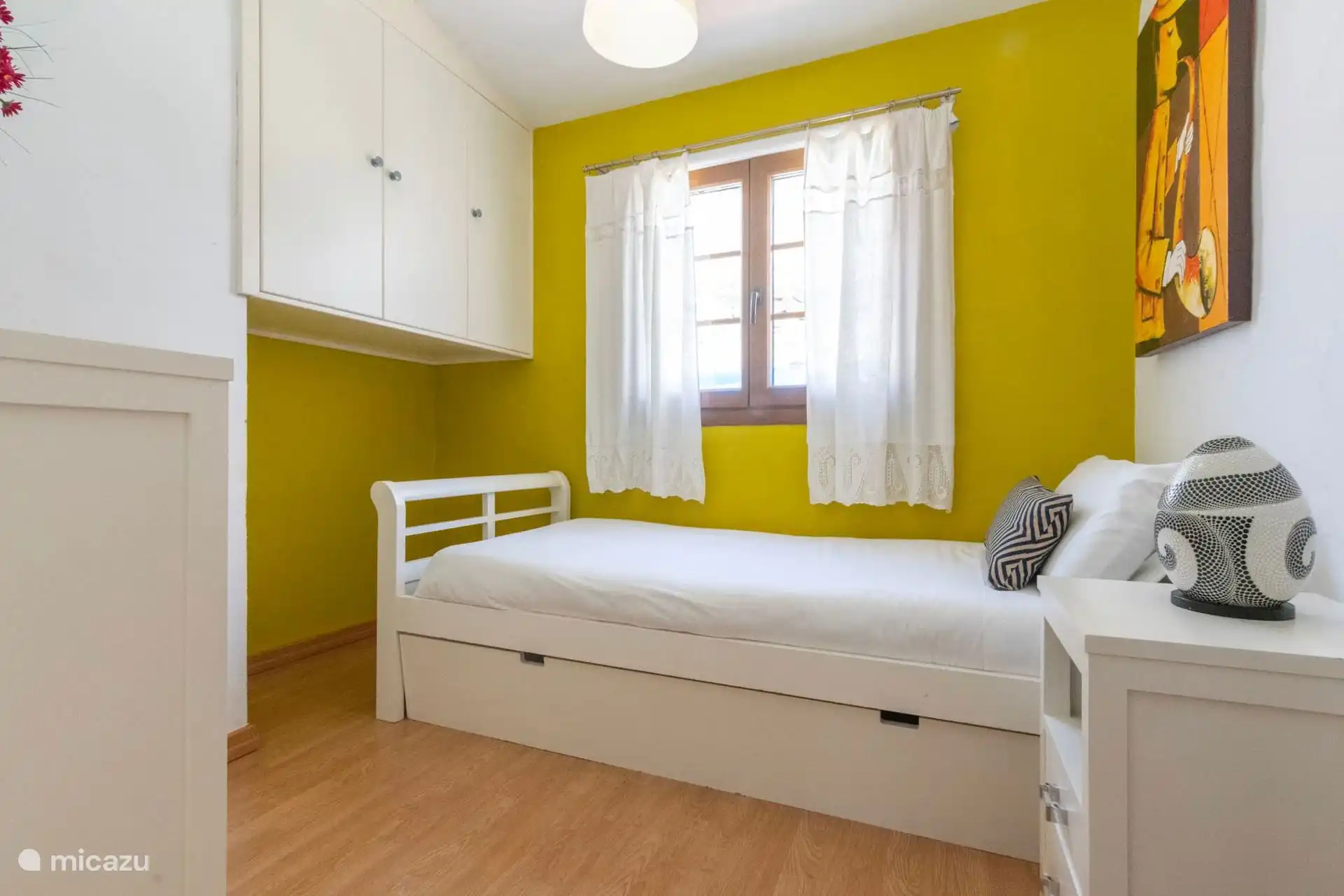 Dormitorio individual con cama nido blanca y armarios.