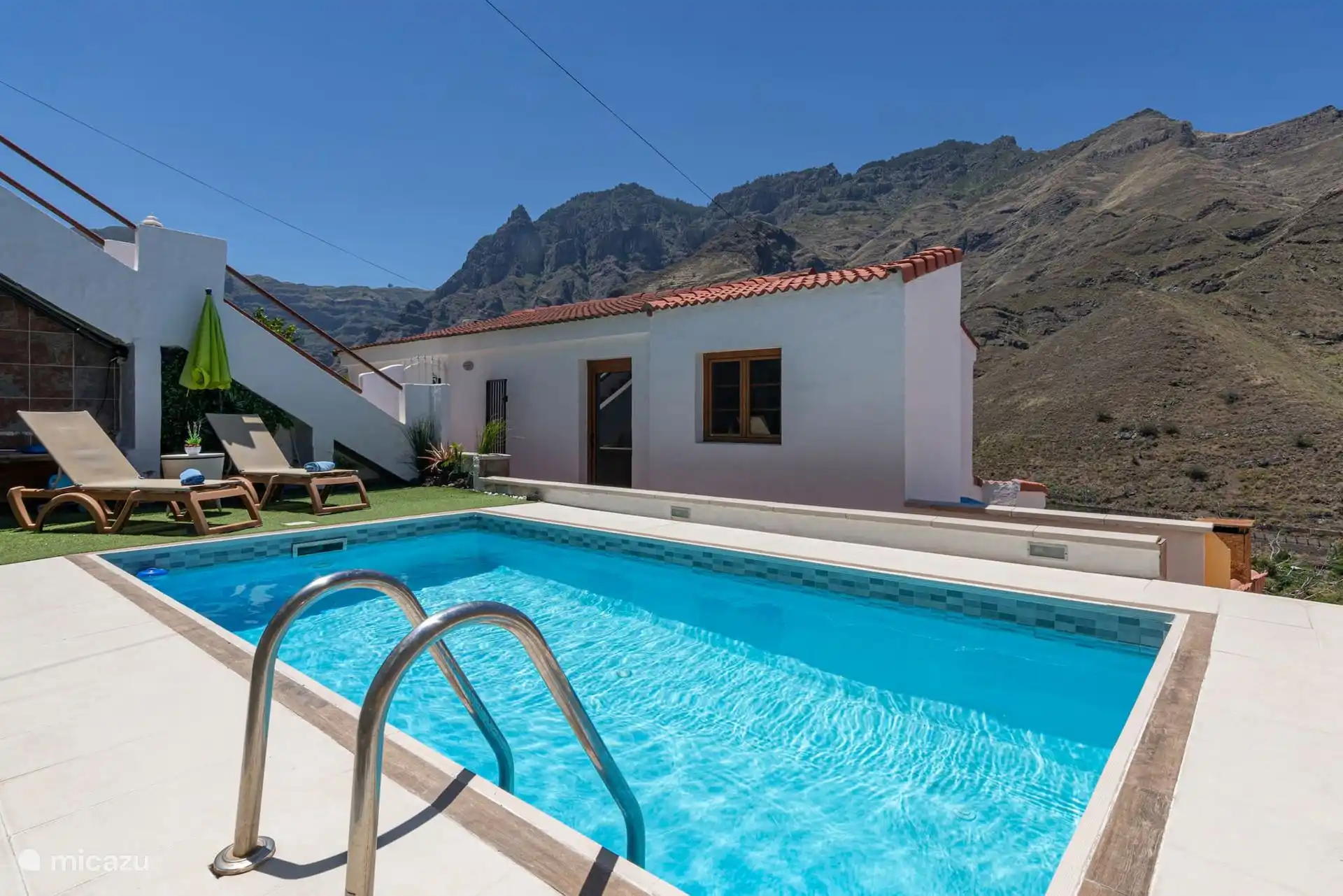 Terraza cubierta con barbacoa de obra y mesa de exterior.