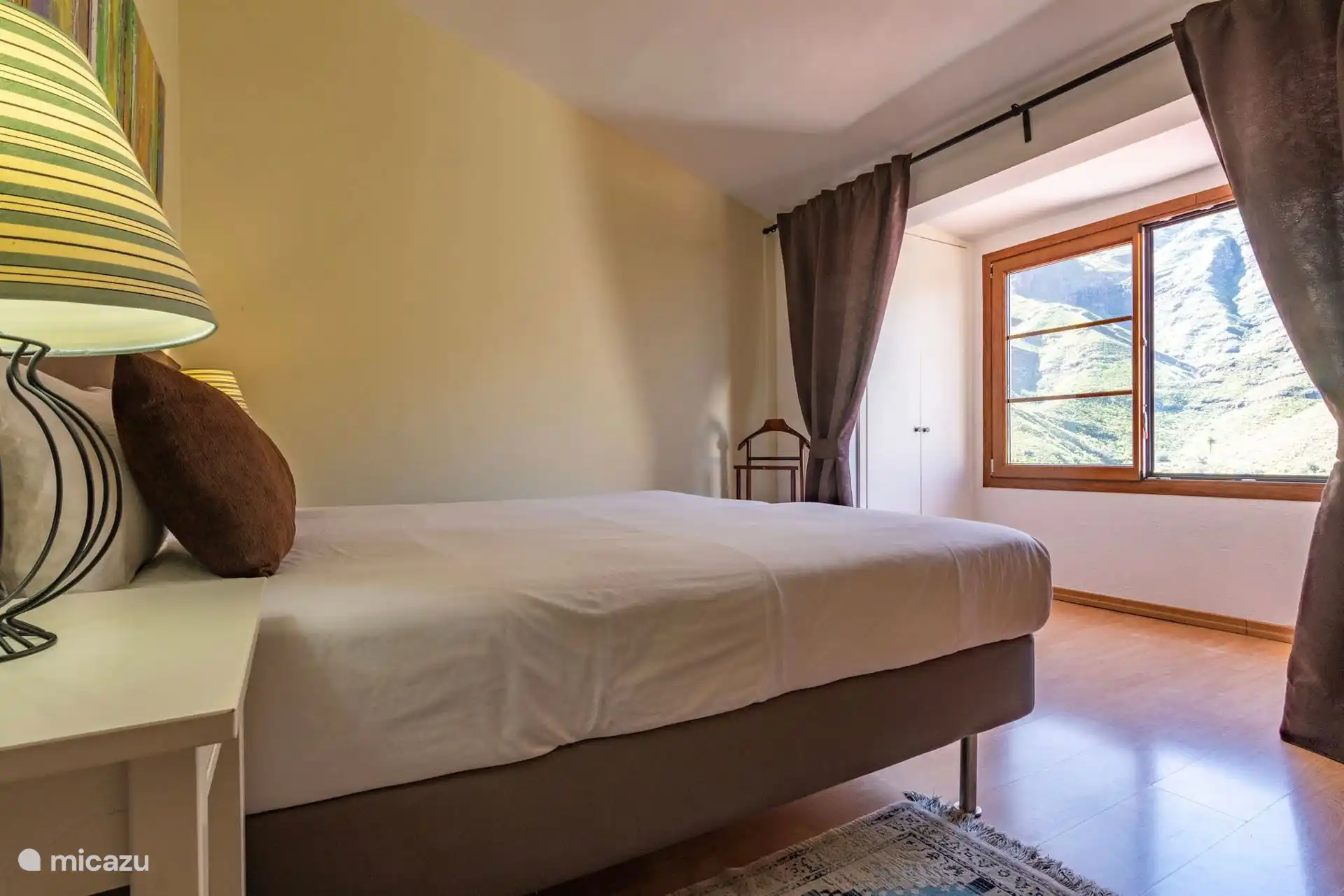 Dormitorio con cama y ventana abierta a la montaña.
