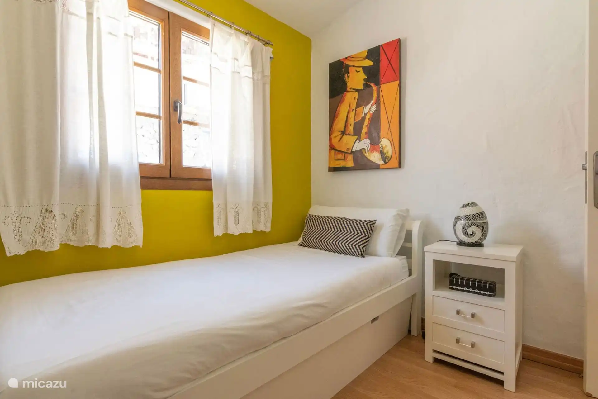Dormitorio individual con ventana de madera y decoración canaria.