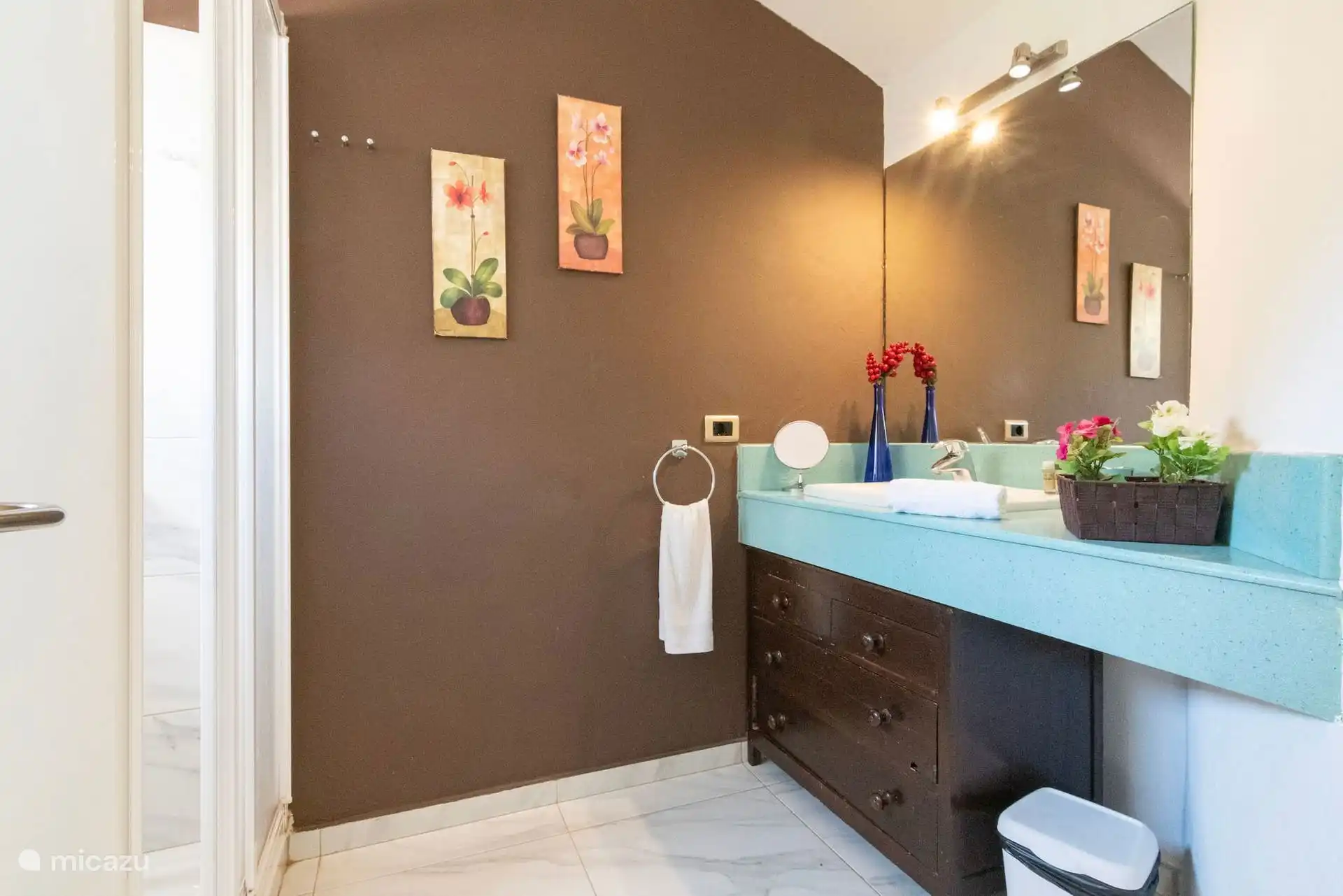 Baño con mueble turquesa, espejo grande y toallas.