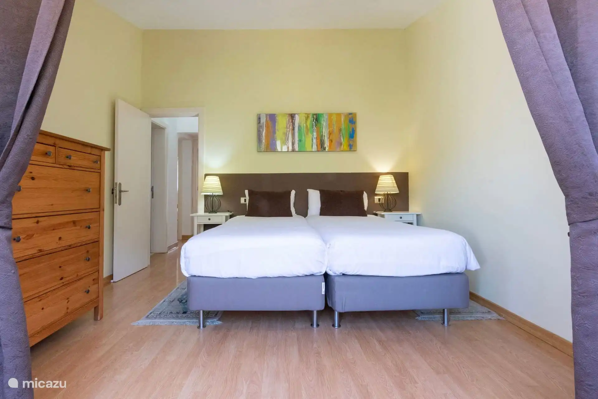 Dormitorio con dos camas individuales, cómoda y cortinas.