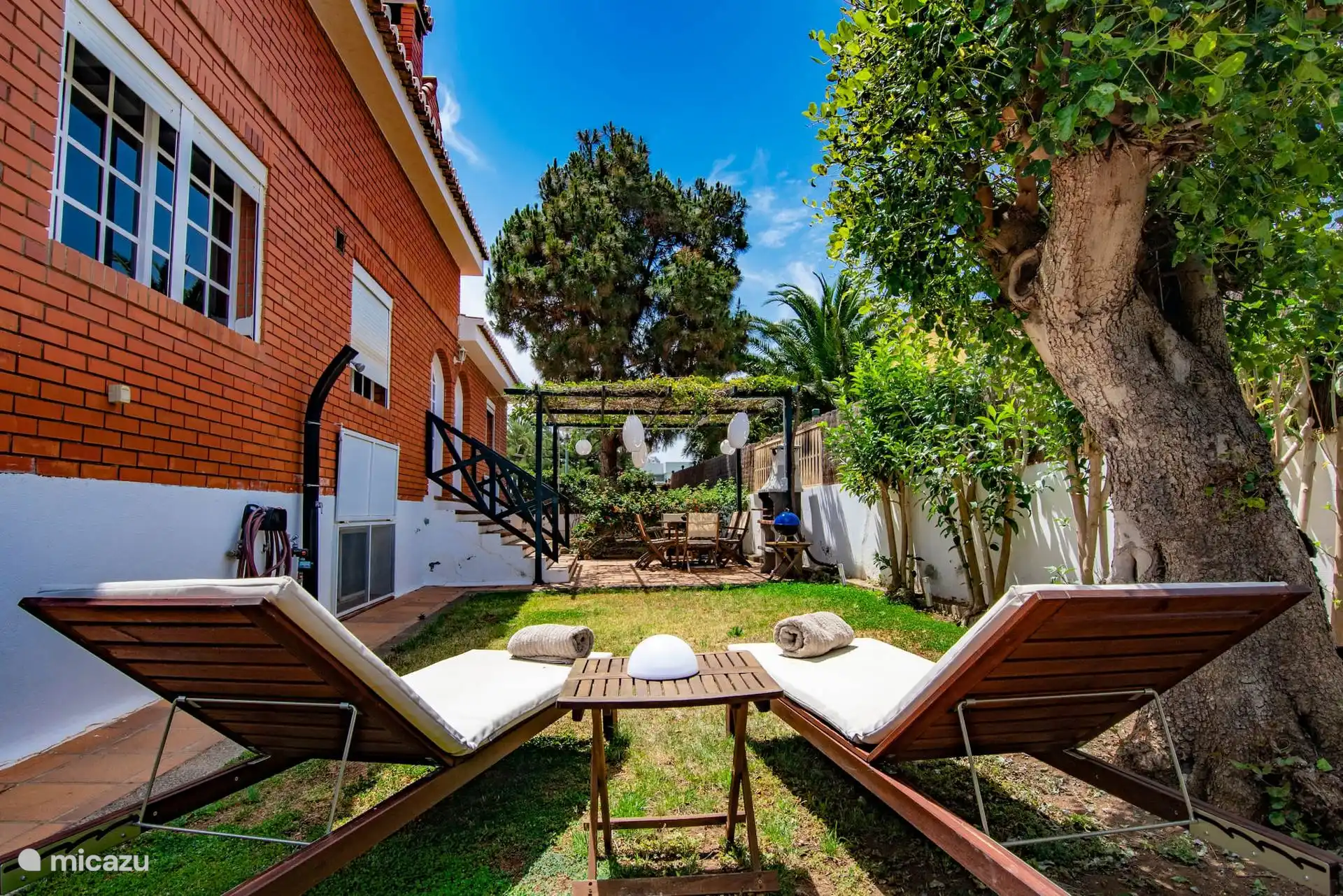 Piscina con escalerilla y tumbonas sobre el césped.