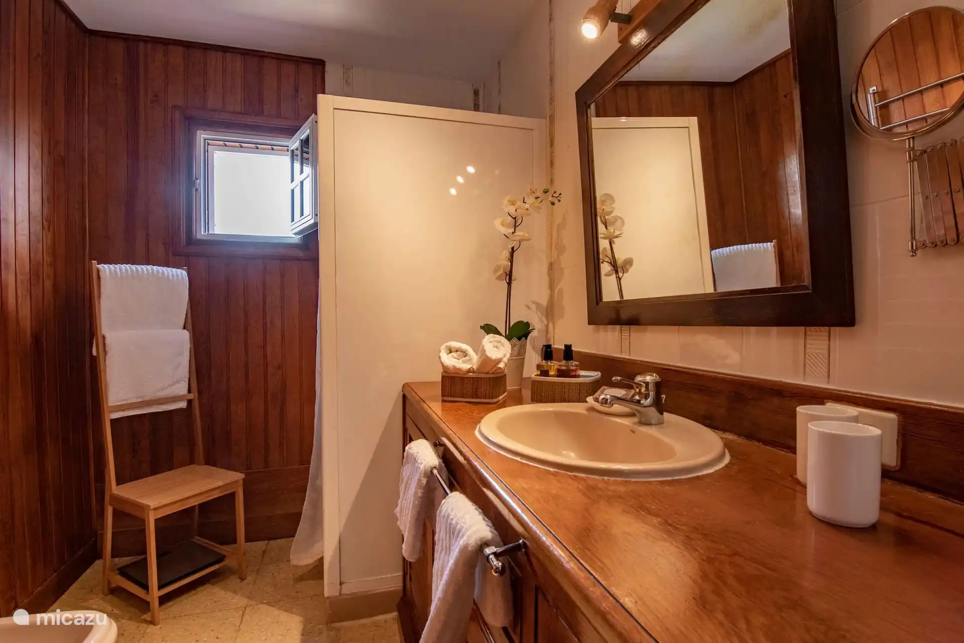 Baño con mueble de madera, espejo grande y bidé.
