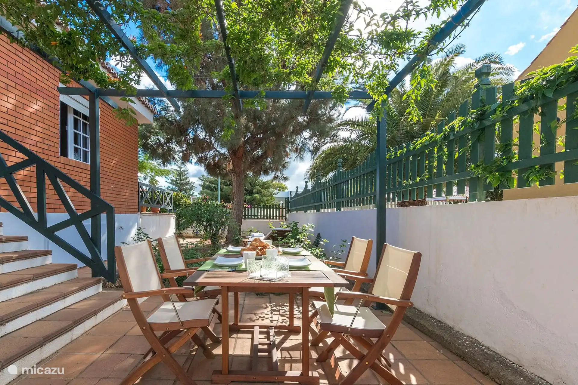 Rincón del jardín con sillas de madera y mesita.