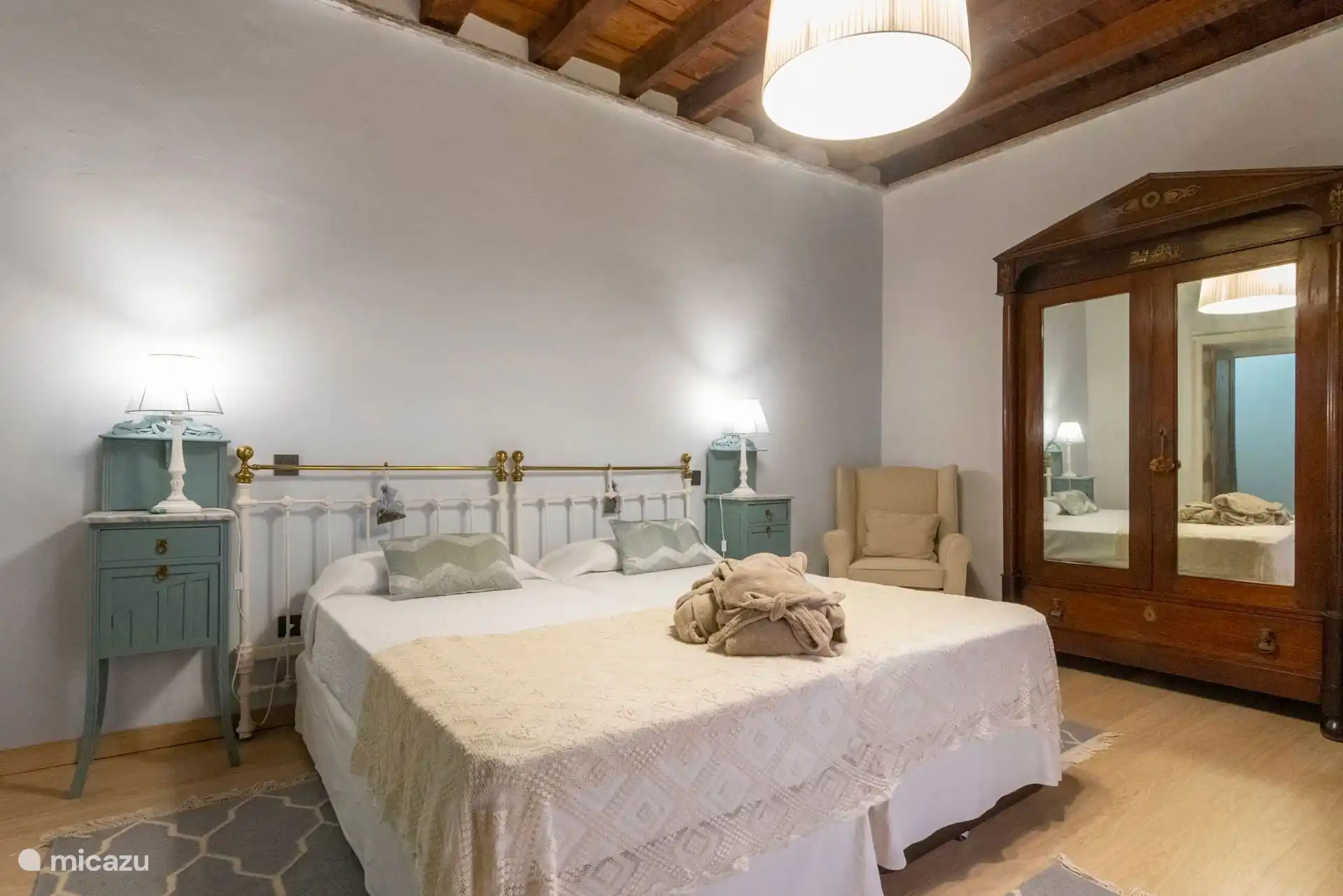 Dormitorio con cama de latón, cómoda verde y armario de luna.