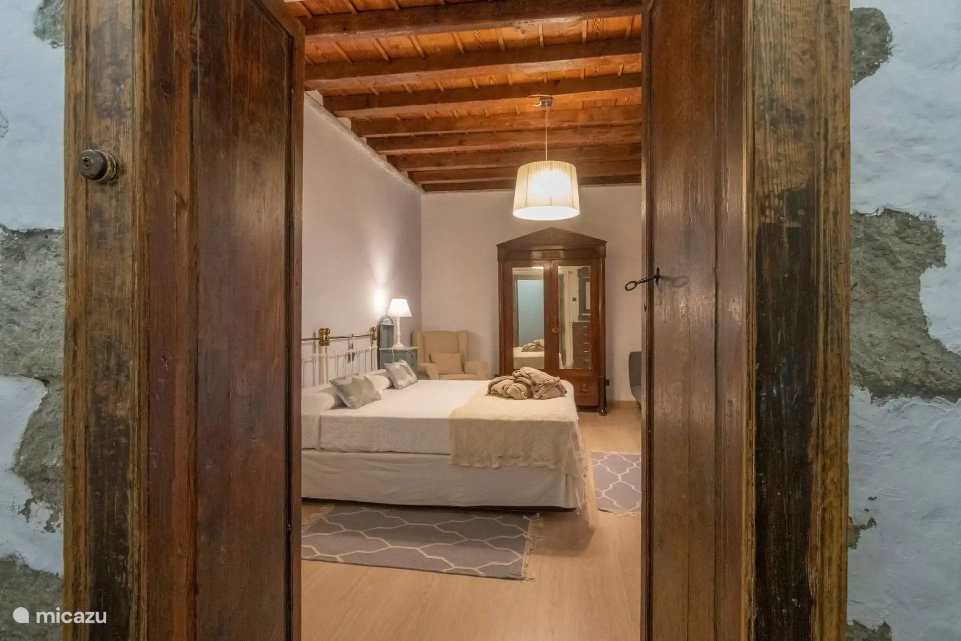 Puerta de madera antigua al dormitorio, con el techo de vigas.