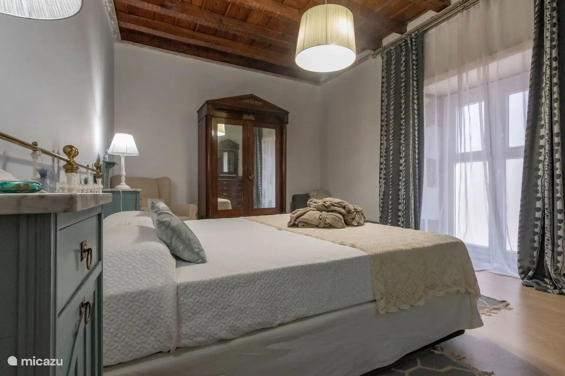 Dormitorio con armario antiguo y ventana con cortinas.
