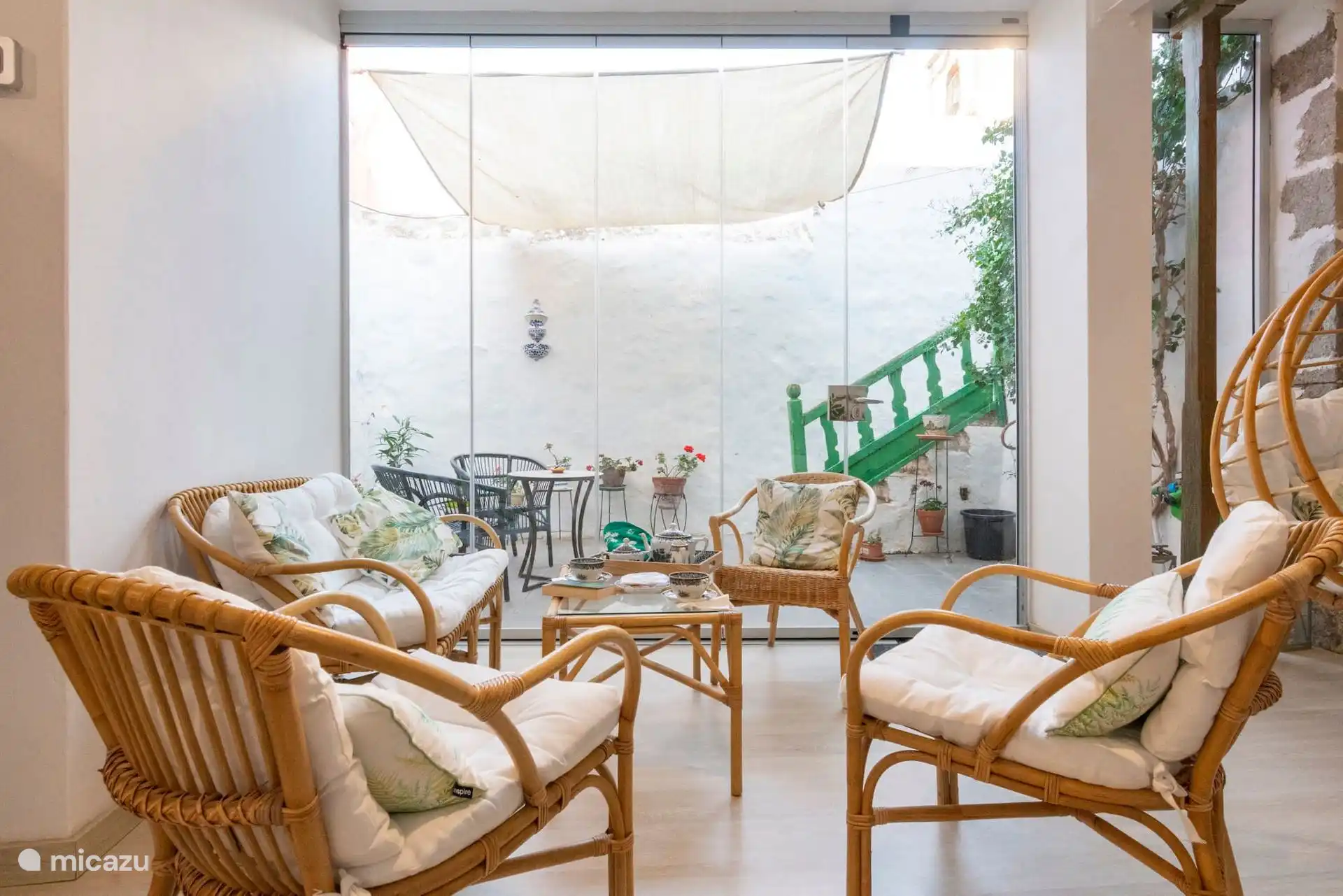 Sillones de ratán en la galería, con la escalera verde detrás.