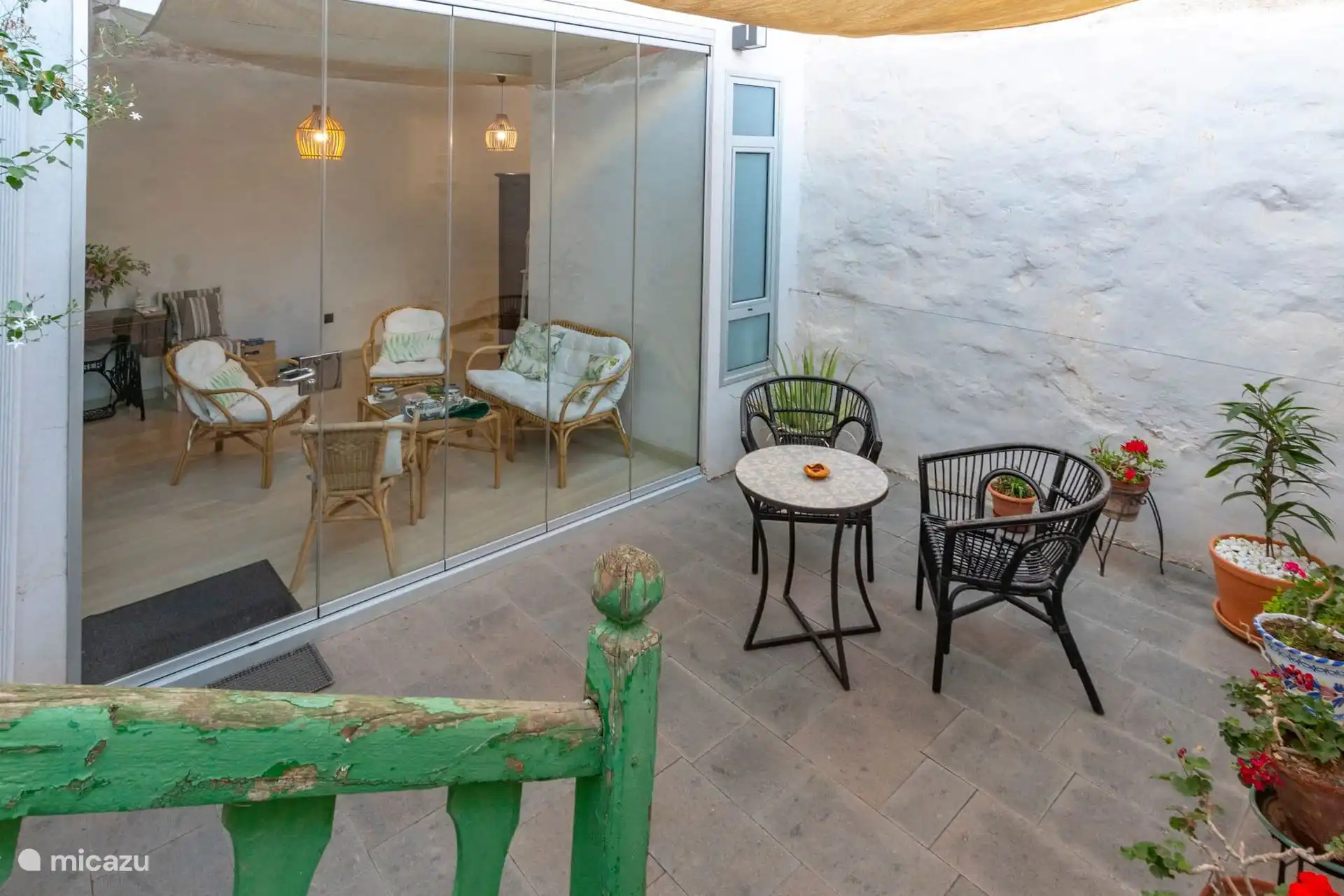 Patio interior con la galería acristalada y mesitas de exterior.