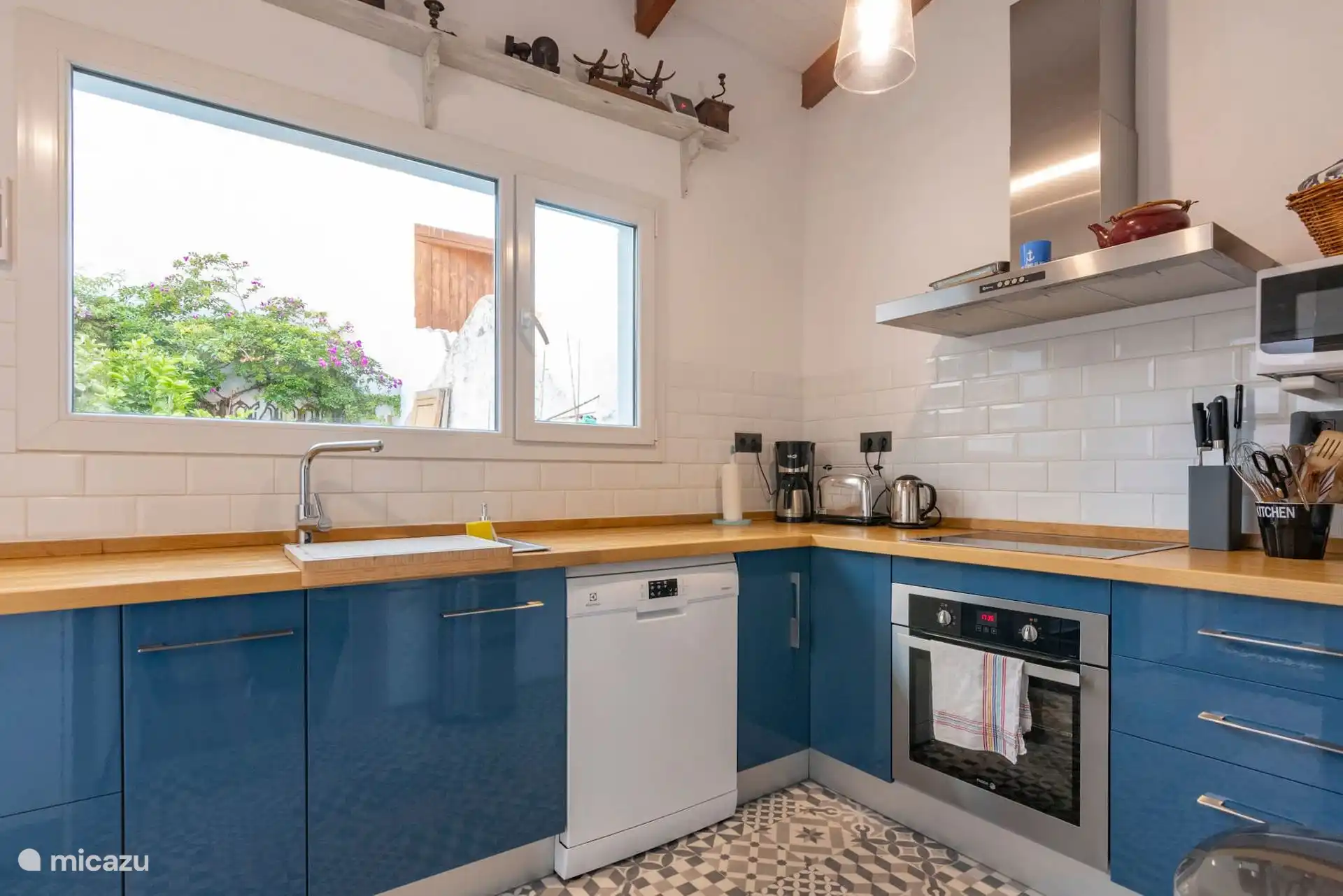 Cocina azul con lavavajillas, horno y encimera de madera.