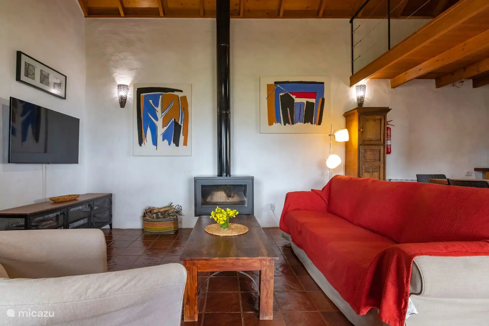 Salón con estufa de leña, sofás y televisión.