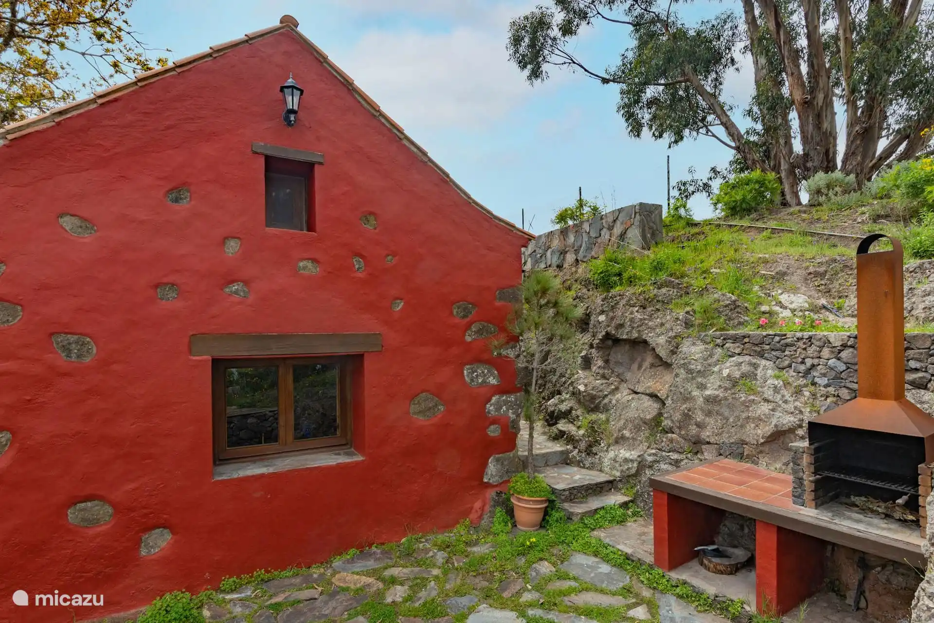 La casa entre la roca volcánica y los eucaliptos.