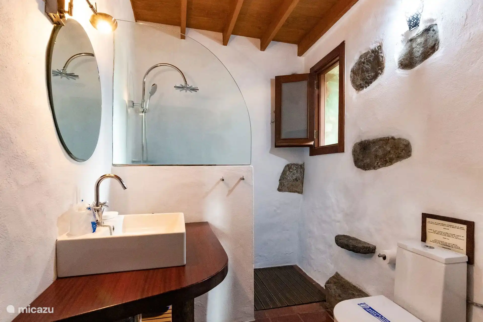 Baño con ducha, lavabo sobre encimera de madera y espejo.