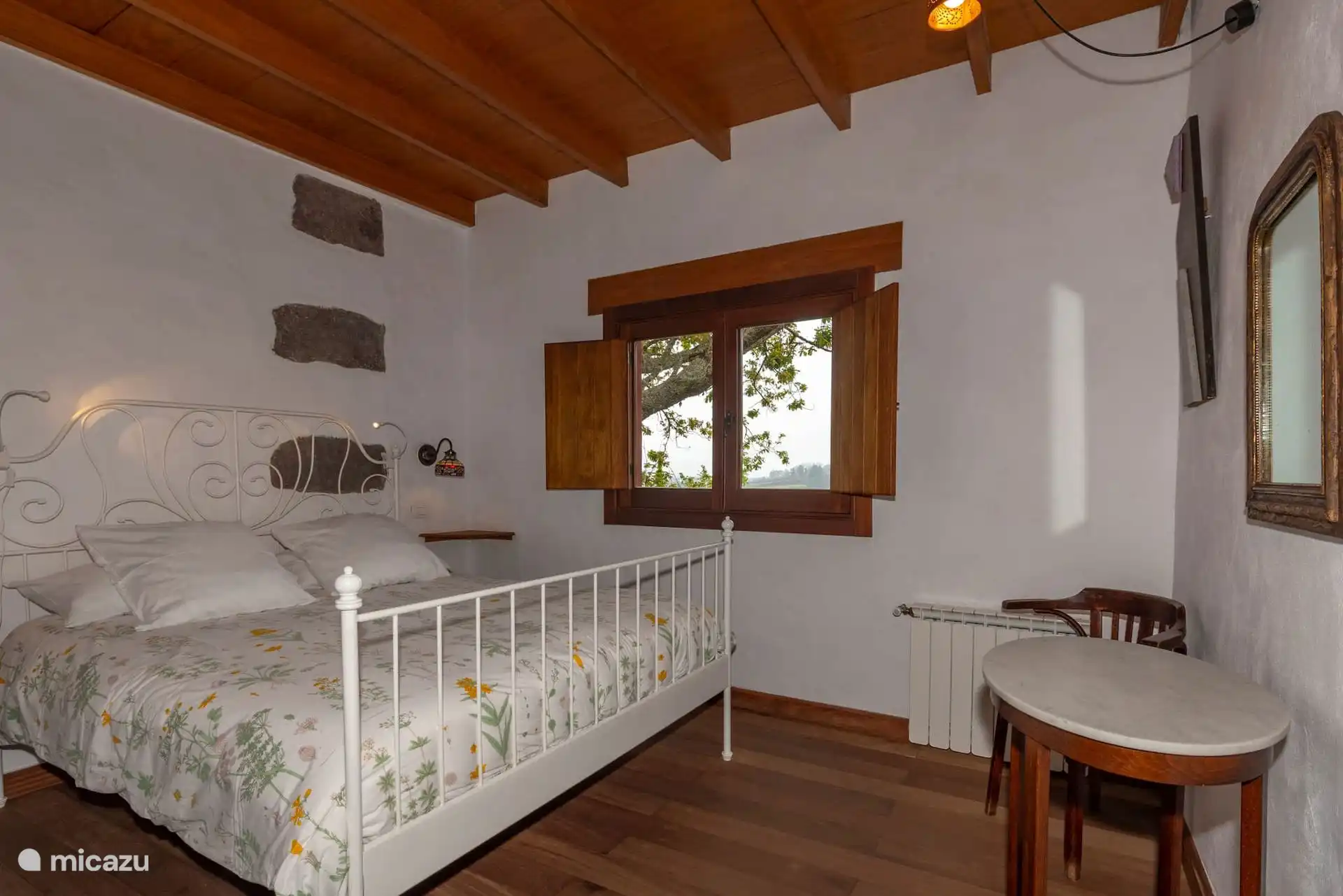 Dormitorio con radiador, mesa y ventana de madera.