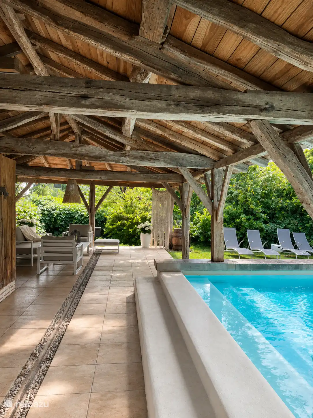 Überdachte Poollounge mit komfortablem Sitzbereich und Poolblick.