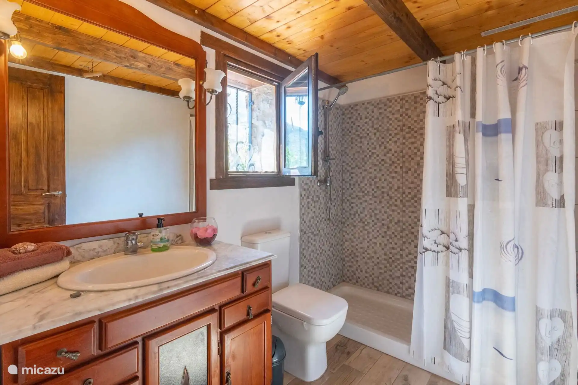 Badezimmer mit Waschbecken auf Holzmöbeln und Dusche mit Vorhang.