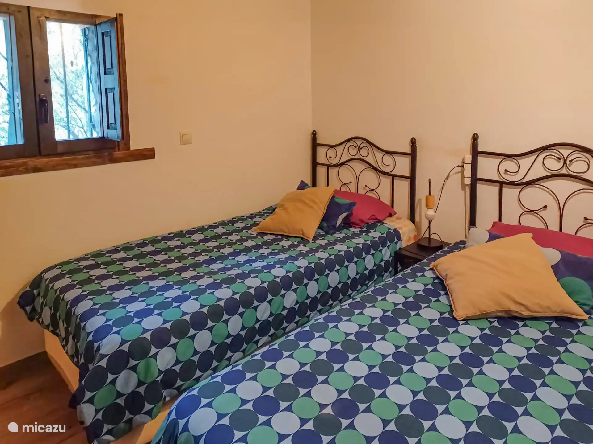 Schlafzimmer mit zwei Einzelbetten und farbigen Bettdecken.