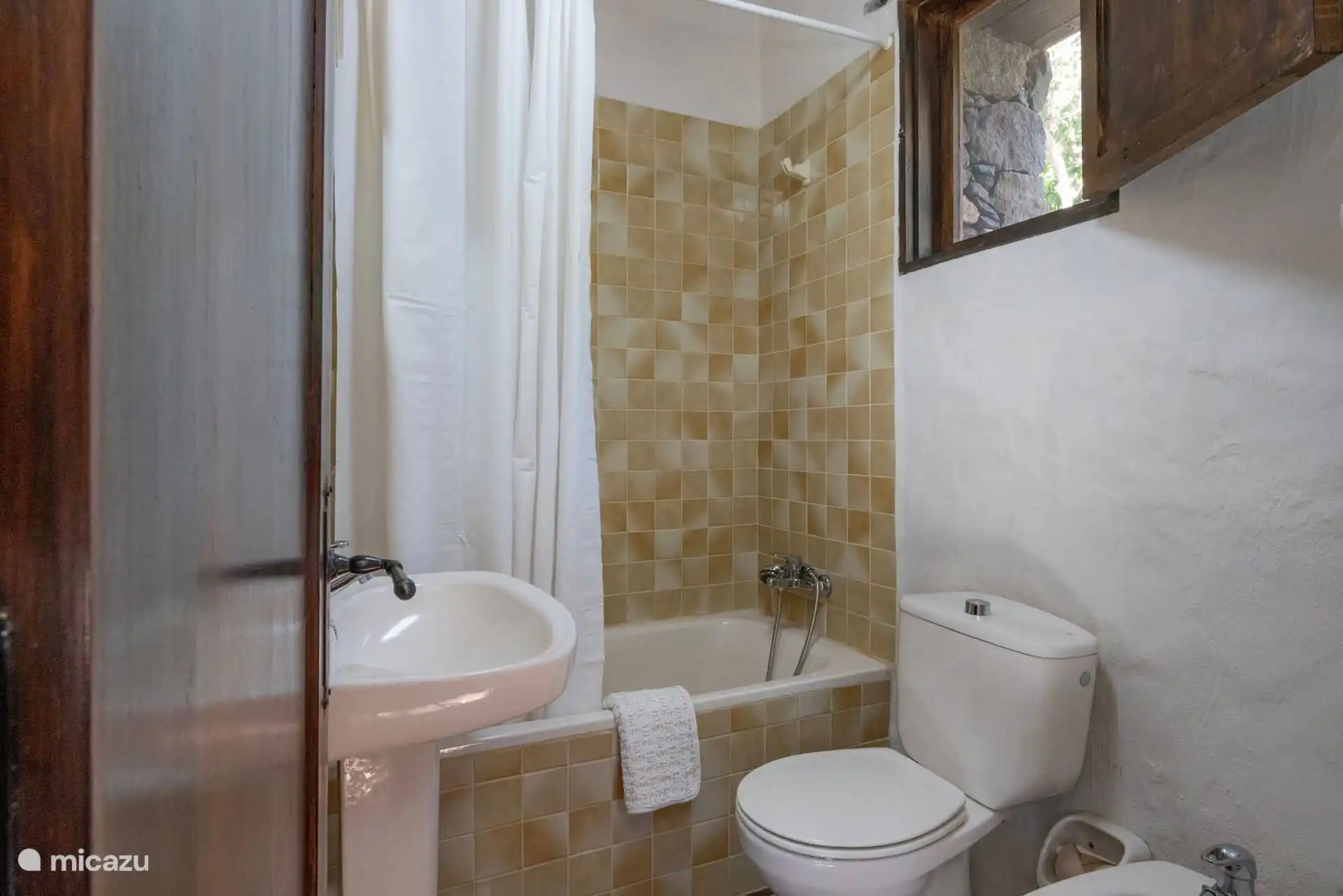 Baño con bañera, bidé y azulejo claro.