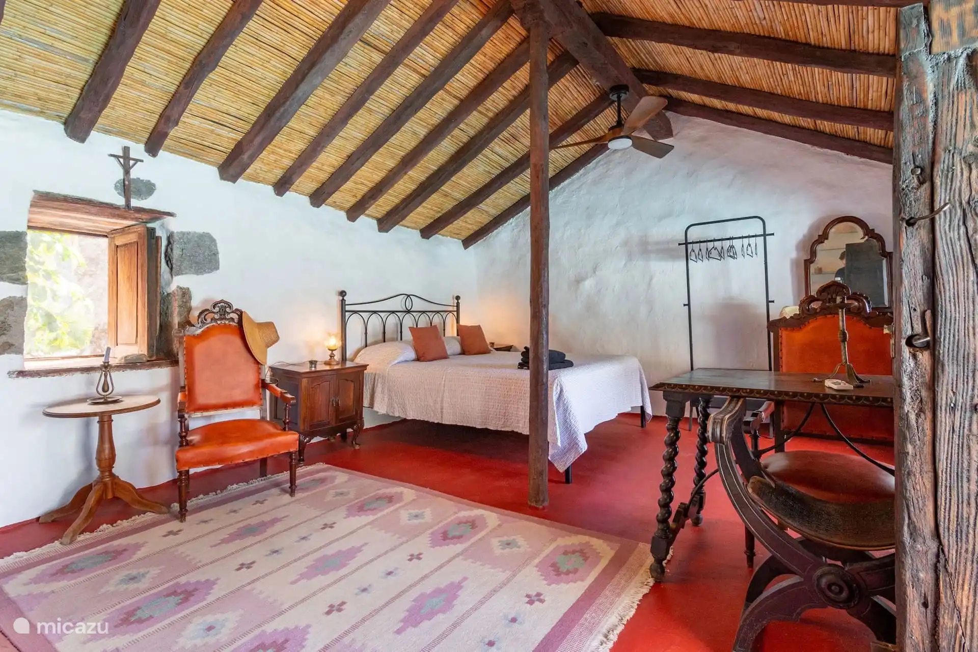 Dormitorio con cama de columnas y escritorio antiguo.