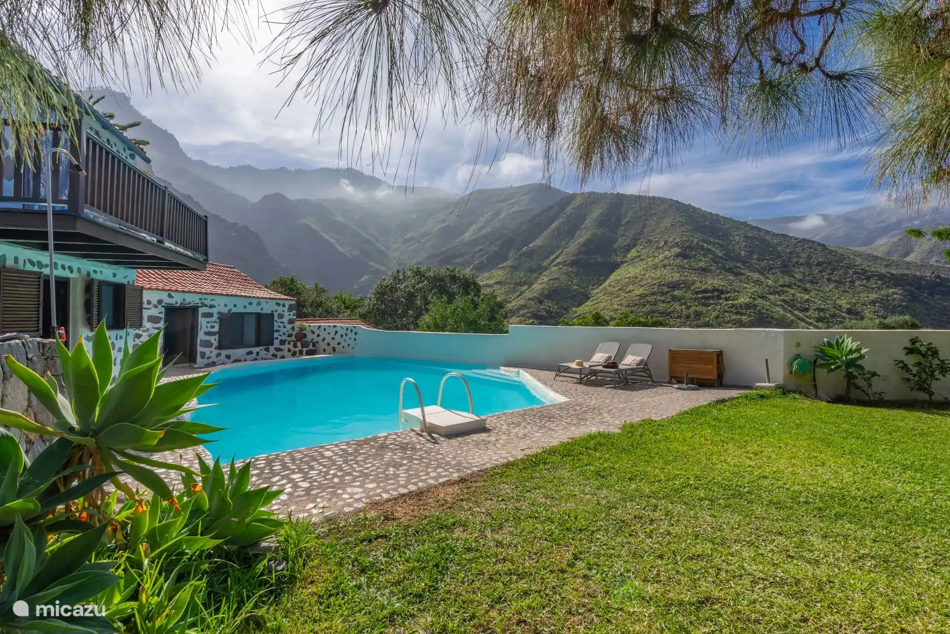 Piscina con el césped alrededor y las montañas del valle.