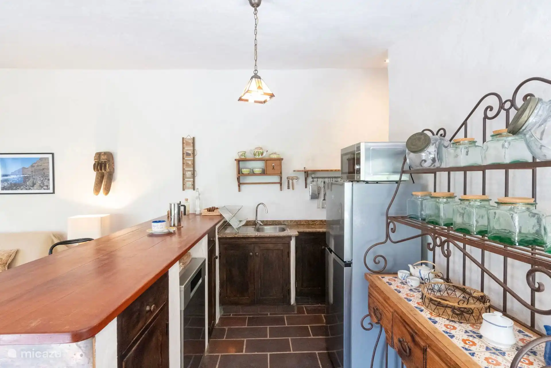 Cocina abierta con barra de madera y nevera grande.