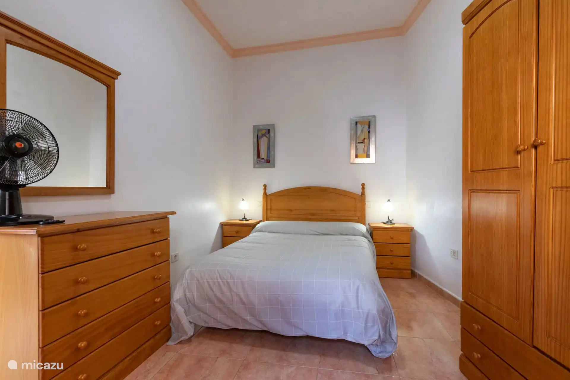Slaapkamer met tweepersoonsbed, kledingkast en ventilator.
