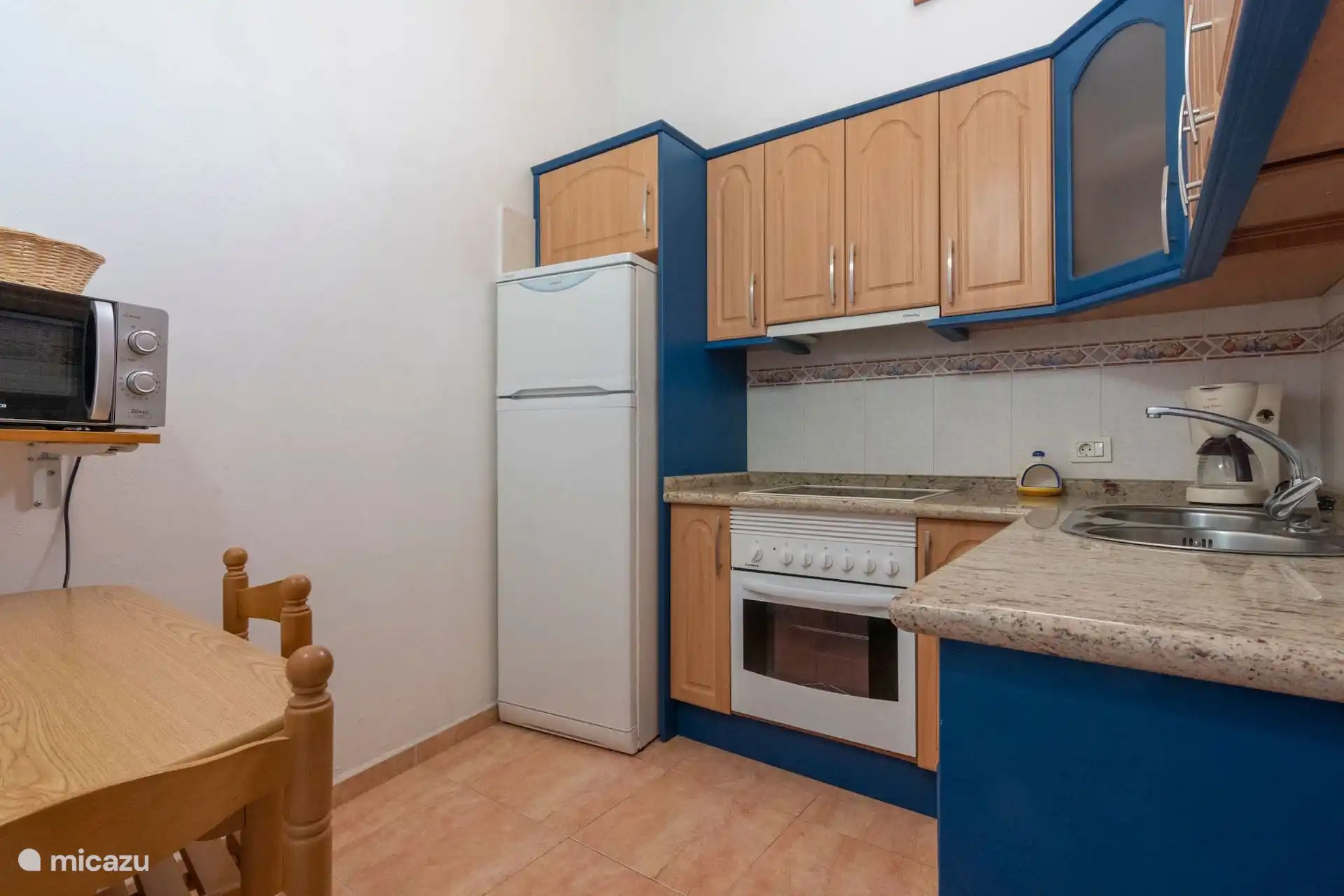 Keuken met oven, magnetron en blauwe kasten.