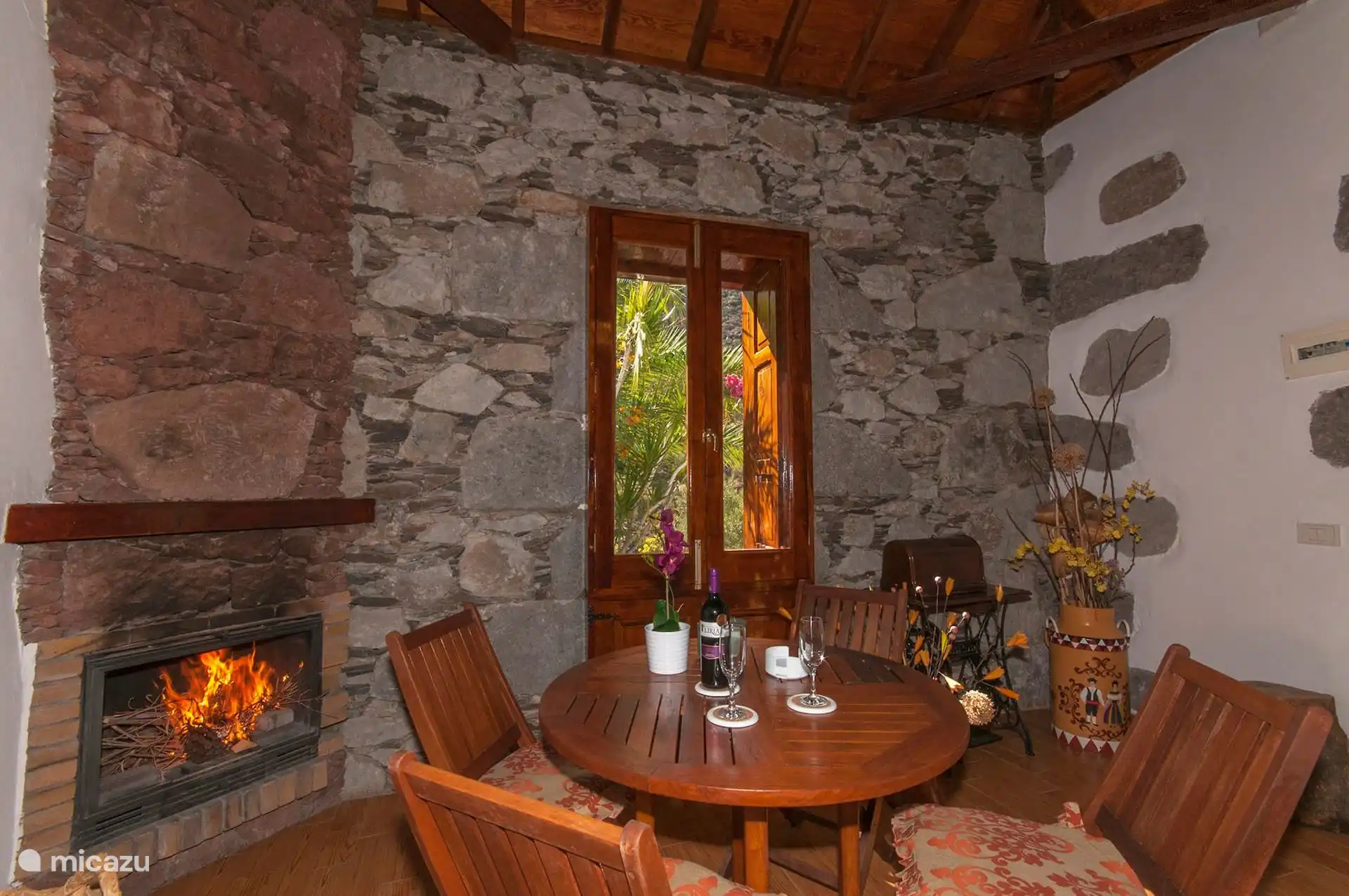 Wohnzimmer mit einem brennenden Kamin und einem runden Holztisch.