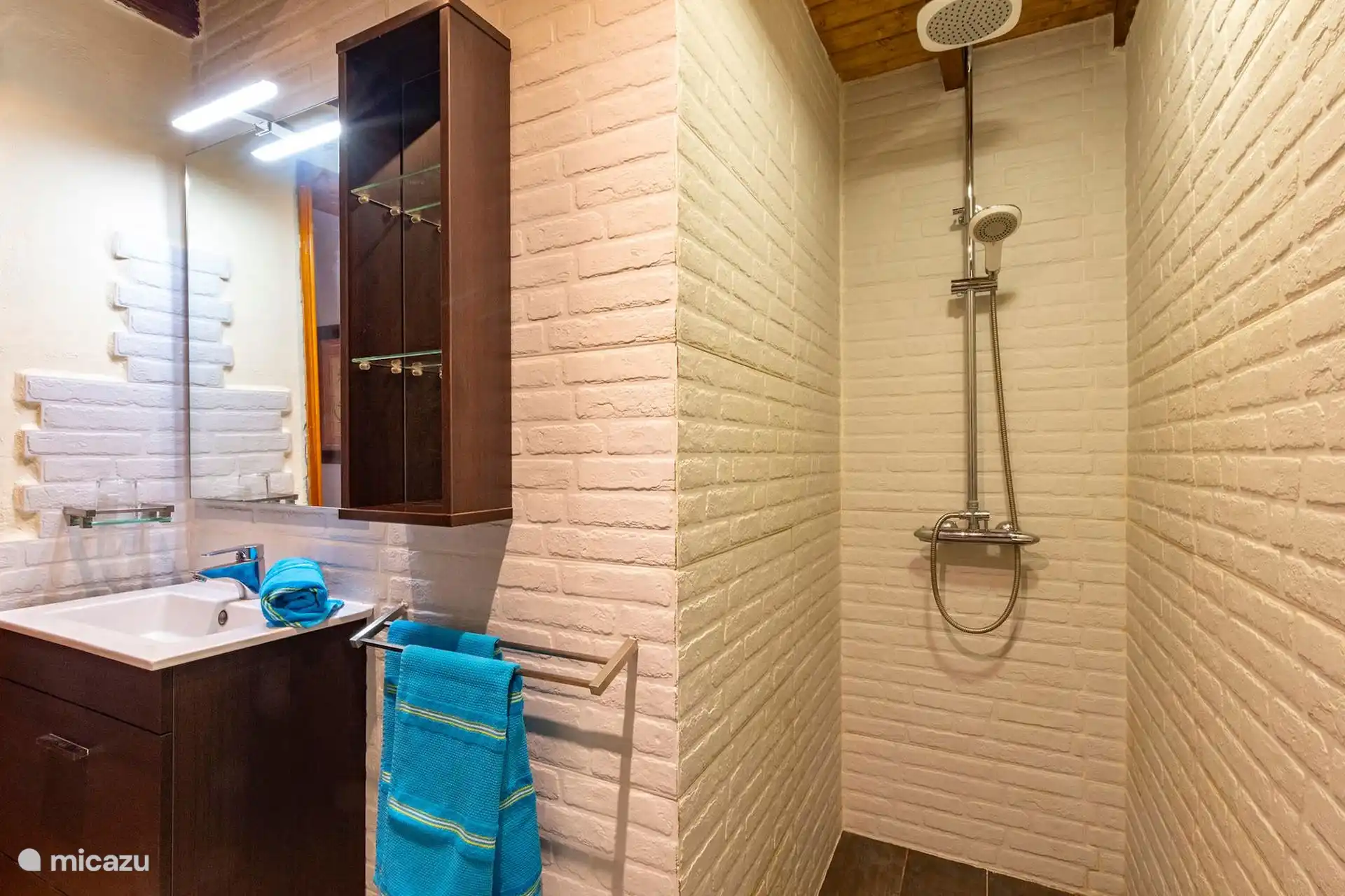 Badezimmer mit eingebauter Dusche und vorbereiteten Handtüchern.