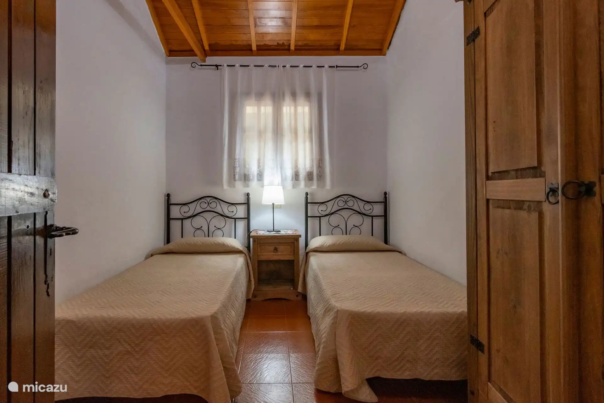 Schlafzimmer mit zwei Einzelbetten und Vorhängen.