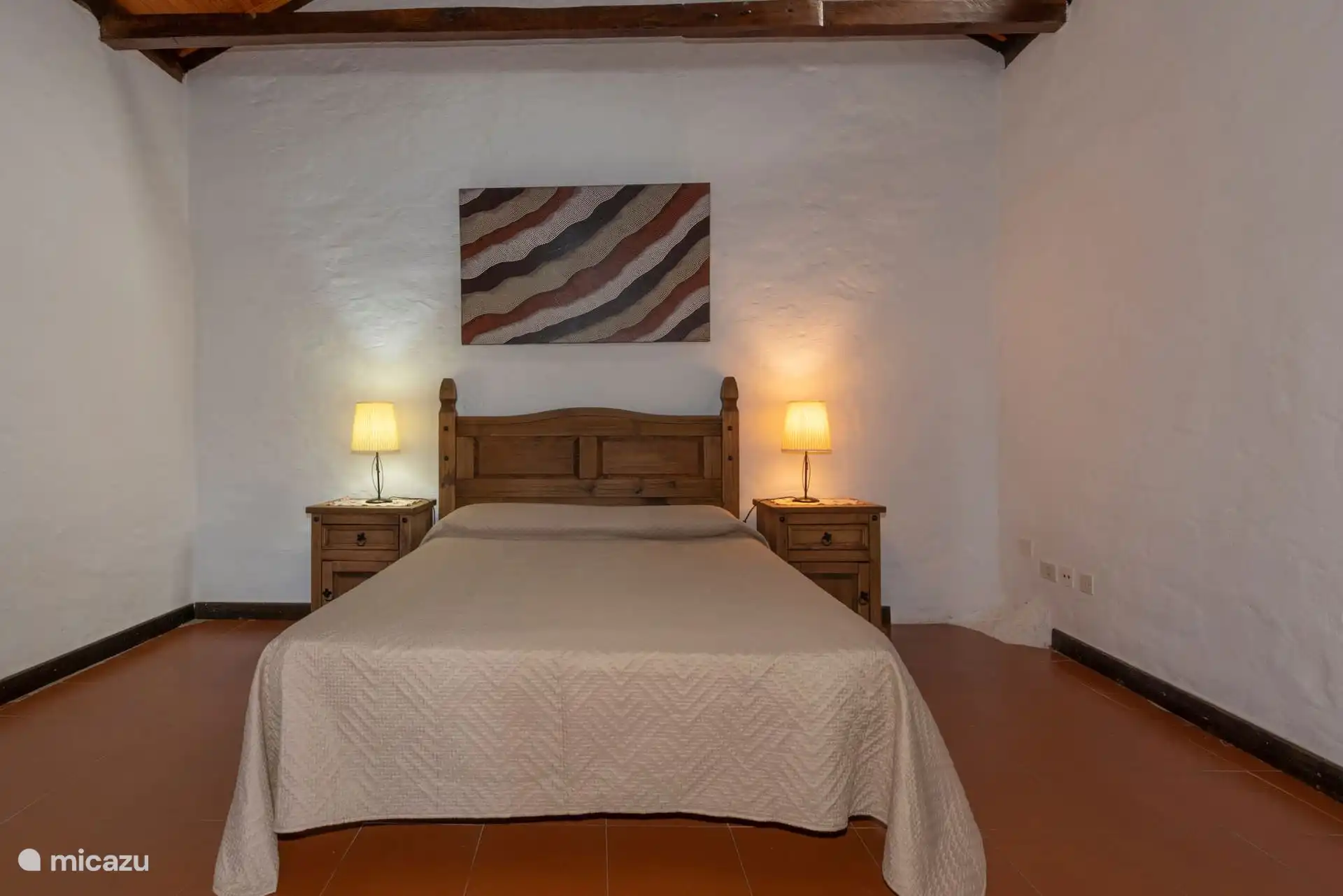 Doppelzimmer mit weiß getünchter Wand und Strahlendecke.