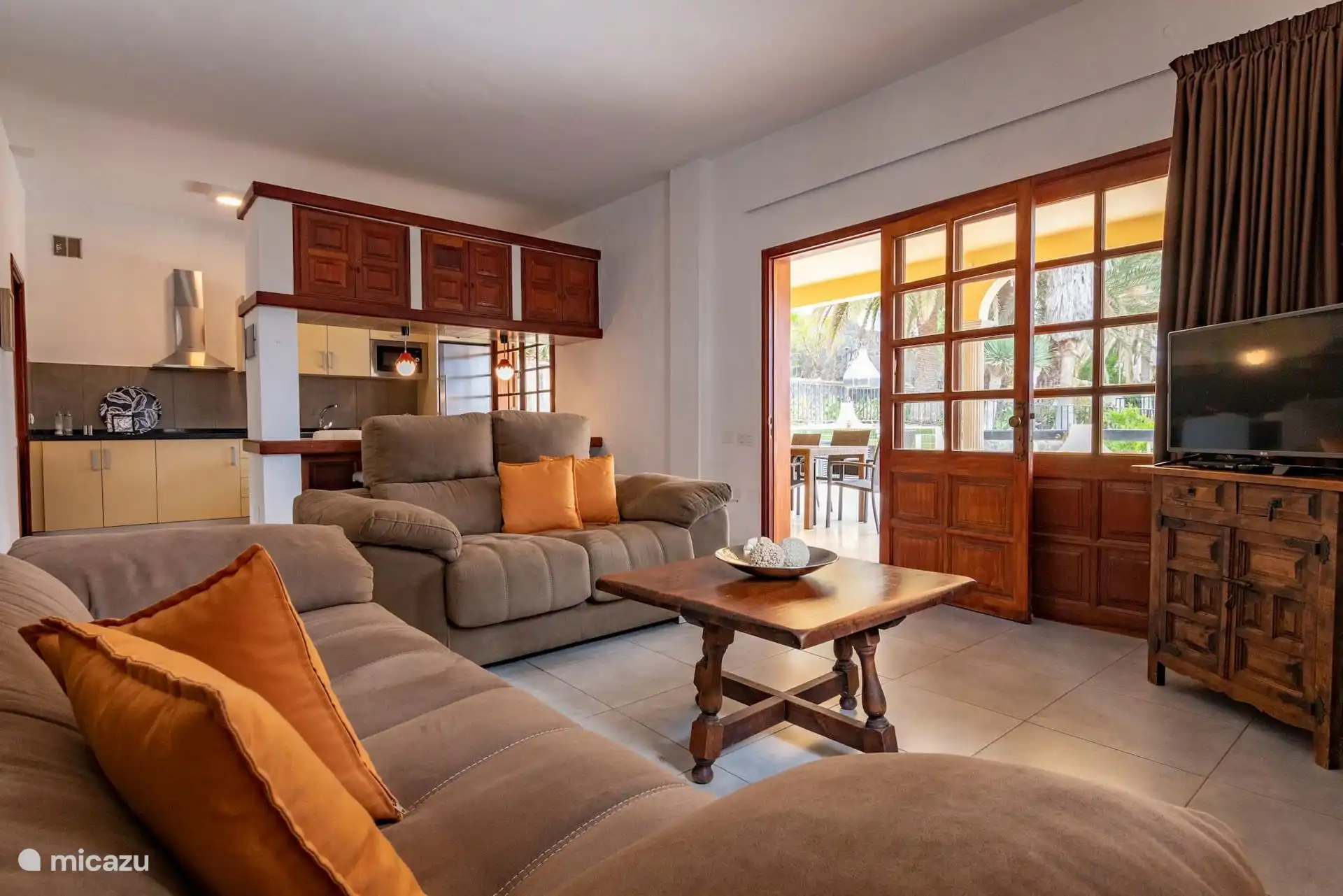 Wohnzimmer mit zwei großen Sofas, Couchtisch, Fernseher und Zugang zur Veranda.
