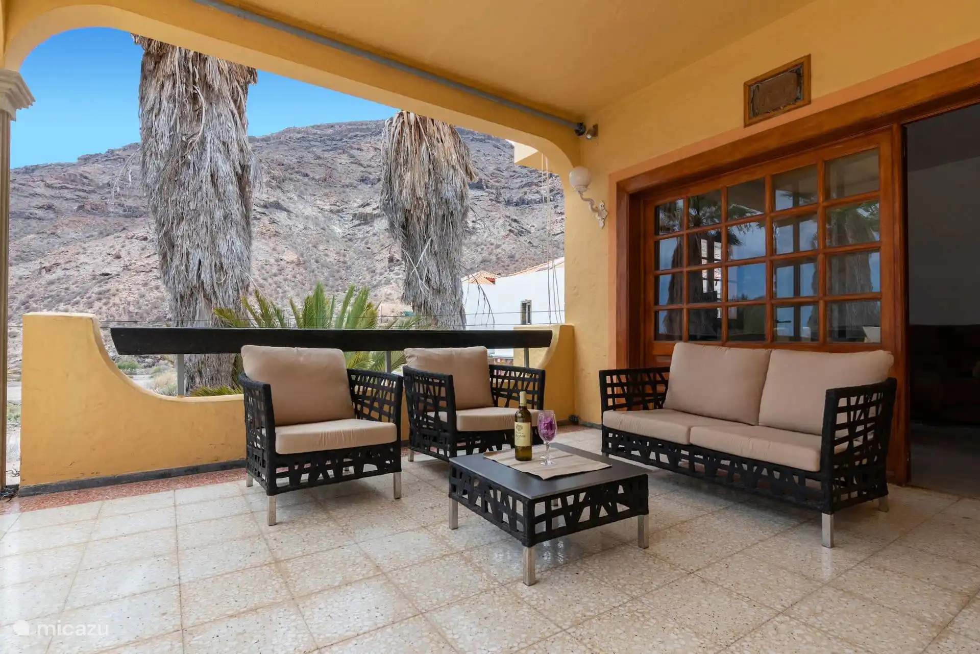 Veranda mit Außensofas und Sesseln, unter den Bögen und mit Blick auf den Berg.